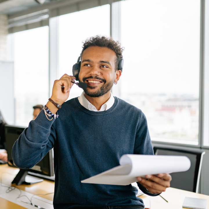 Smiling call center agent wearing a headset verifying and routing a live homeowner service call from the office
